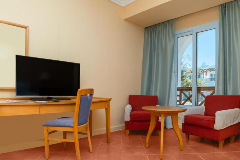Habitación con salón, televisor, sillones rojos y balcón con vistas en Jaz Sharm Dream Vacation Club