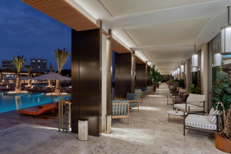 Terraza lounge con sofás junto a la piscina iluminada del The Landmark Nicosia Autograph Collection