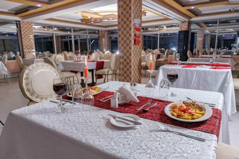 Restaurante elegante con mesas decoradas con velas y vino tinto en el Isiolo Landmark Hotel
