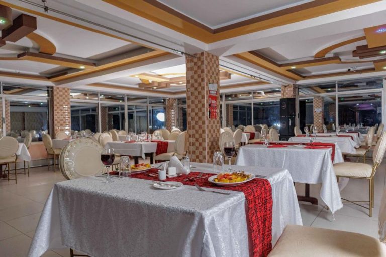 Elegante restaurante del Isiolo Landmark Hotel con mesas en blanco y rojo preparadas para cenar