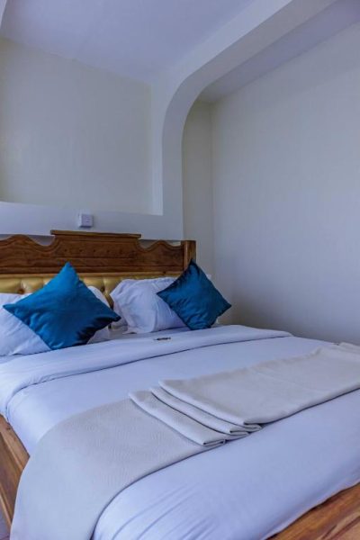 Habitación doble con cama matrimonial y almohadas azules en Isiolo Landmark Hotel