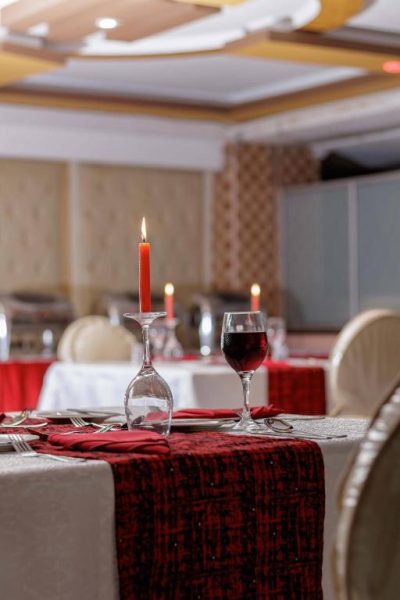 Mesa elegante con velas rojas y copa de vino tinto en el restaurante del Isiolo Landmark Hotel