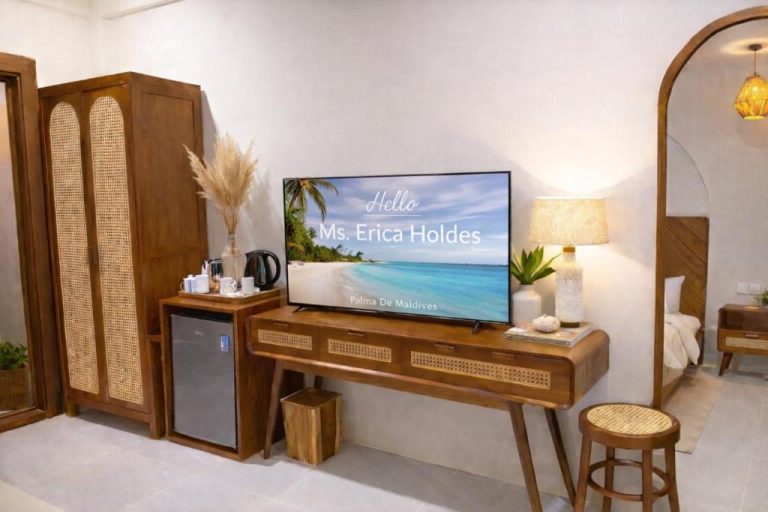 Habitación con televisor de bienvenida personalizado y mobiliario de madera en Palma De Maldives