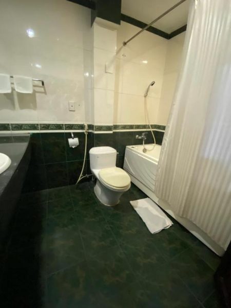 Baño completo con bañera, ducha y sanitarios del Orient Hotel con azulejos en verde y blanco