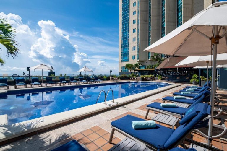 Piscina exterior con tumbonas y sombrillas en la terraza del hotel Catalonia Santo Domingo