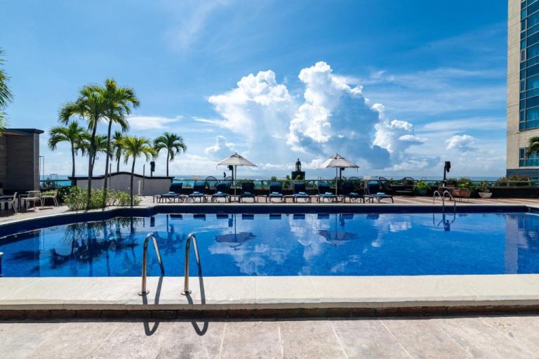 Piscina exterior con tumbonas y sombrillas del Catalonia Santo Domingo con vistas al mar Caribe