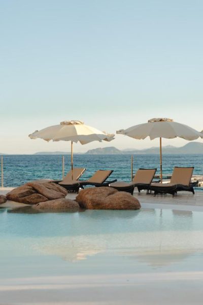 Piscina infinita con tumbonas y sombrillas frente al mar en Gabbiano Azzurro Hotel & Suites