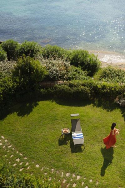 Jardín con tumbonas y vistas al mar del Gabbiano Azzurro Hotel & Suites en Cerdeña
