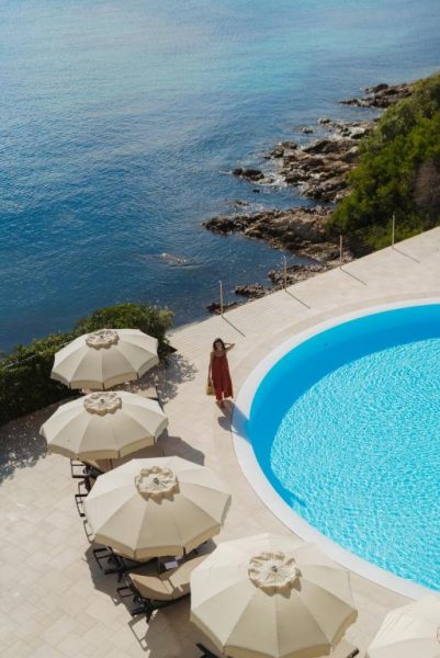 Piscina exterior con tumbonas y sombrillas del Gabbiano Azzurro Hotel & Suites frente al mar de Cerdeña