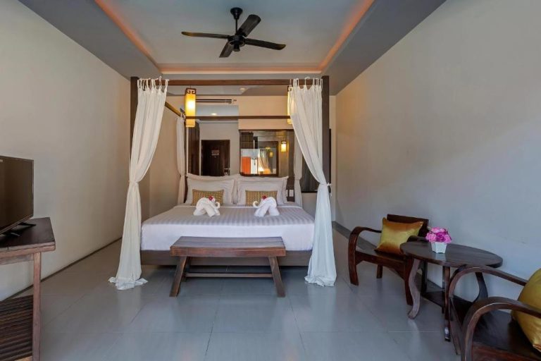 Habitación con cama con dosel y cortinas blancas en el Phuketa Hotel Phuket Town