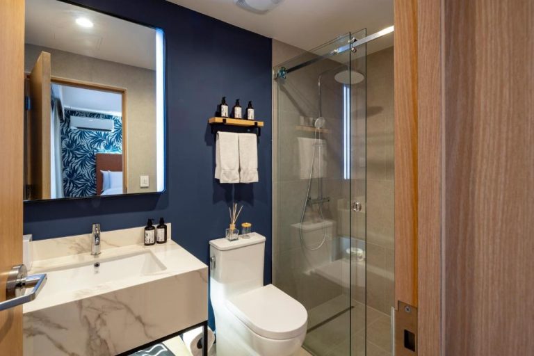 Baño moderno con ducha de cristal y lavabo de mármol en el voco Surfside Aruba by IHG