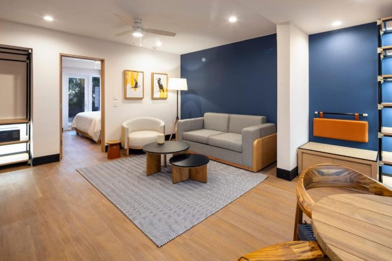 Suite con sala de estar moderna y pared azul en el voco Surfside Aruba by IHG