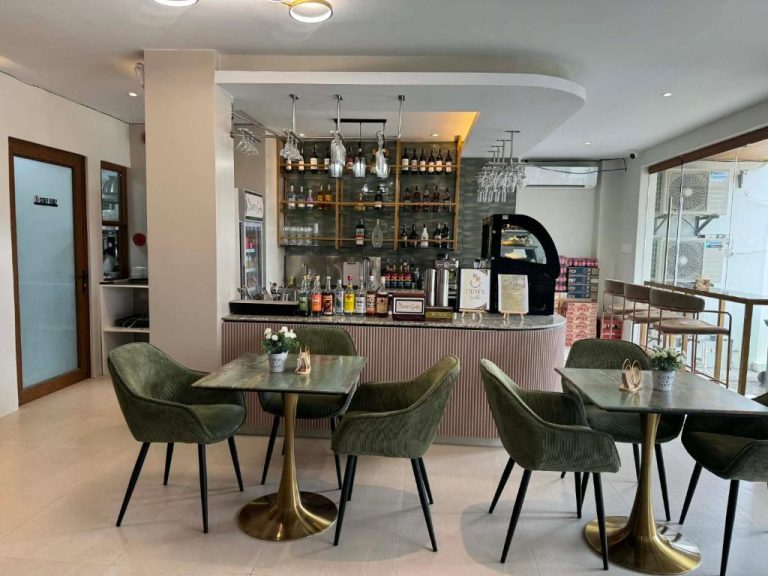 Bar y salón del restaurante de Olive's Suites con mesas elegantes, sillas verdes y barra de cócteles