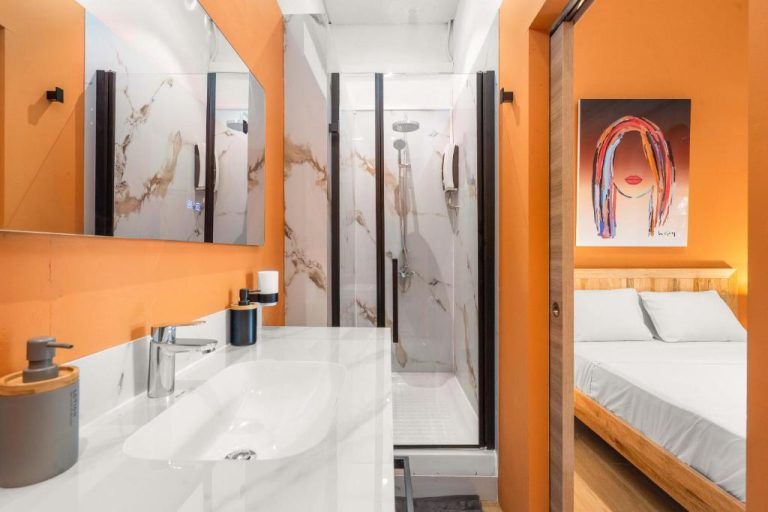 Baño moderno con ducha de mármol y paredes naranjas en Aroma Plaza Boutique Hotel