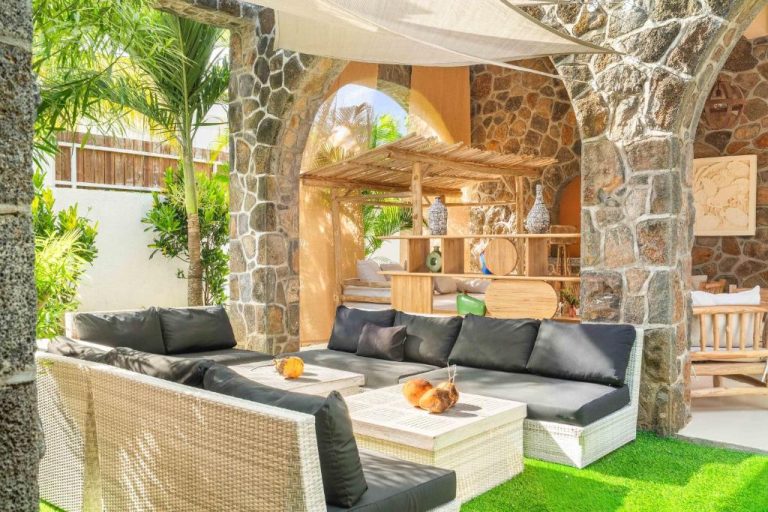 Terraza exterior con sofás de ratán y arcos de piedra natural en Aroma Plaza Boutique Hotel
