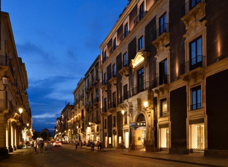 Fachada barroca iluminada del Palace Catania UNA Esperienze al anochecer en el centro histórico de Catania