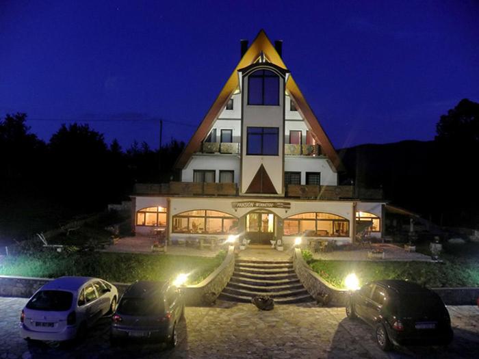 Fachada nocturna iluminada del hotel Sobe Vrata Plitvica con arquitectura triangular y aparcamiento