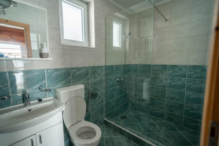 Baño moderno con ducha de cristal y azulejos verdes del Hotel Sjever