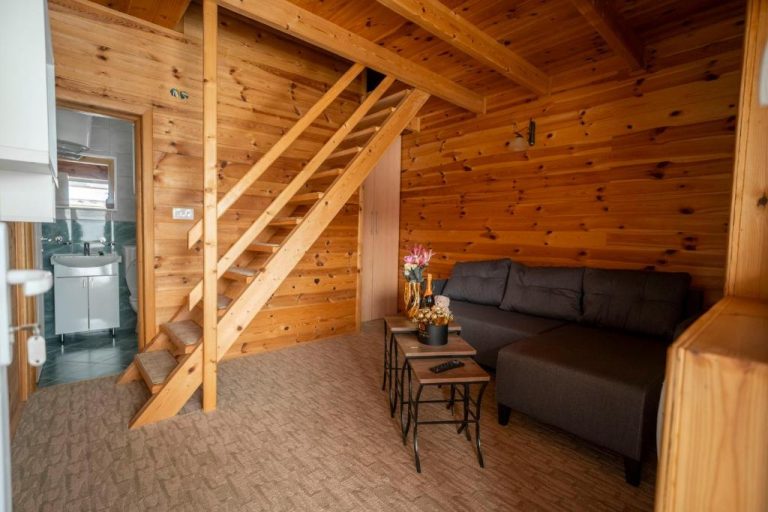 Salón rústico con sofá y escalera de madera en cabaña del Hotel Sjever