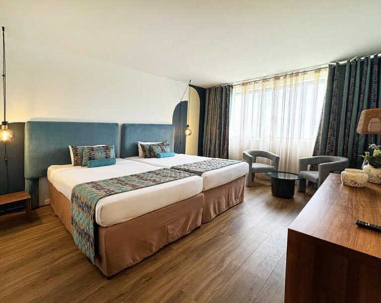 Habitación twin moderna con cabecero azul y suelo de madera en Karibea La Valmenière Hôtel