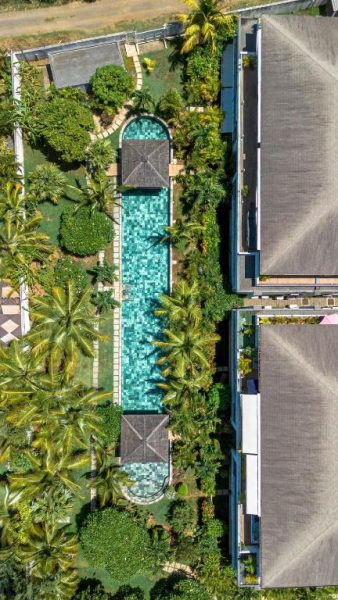 Vista aérea de la piscina infinity rodeada de jardines tropicales en Aroma Plaza Boutique Hotel