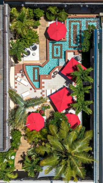 Vista aérea de la piscina infinity y jardines tropicales del Aroma Plaza Boutique Hotel con sombrillas rojas
