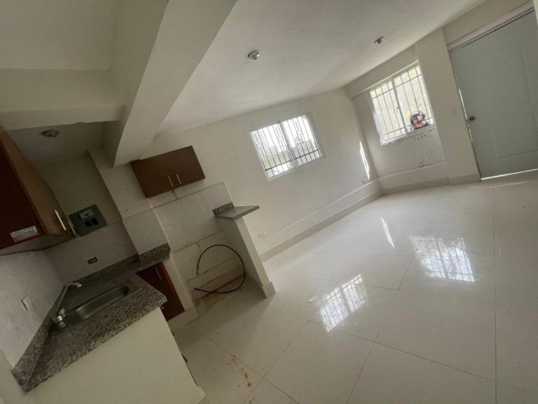 Cocina y sala de estar vacía con piso de mármol blanco y ventanas con rejas en Bohio RD