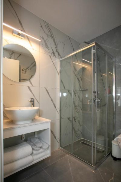 Baño moderno con ducha de cristal y revestimiento de mármol en Best Western Plus Larco Hotel