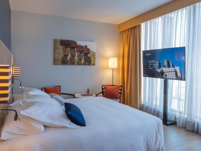 Habitación doble con cama king size y televisor del Debaines Hotel Santiago en Chile