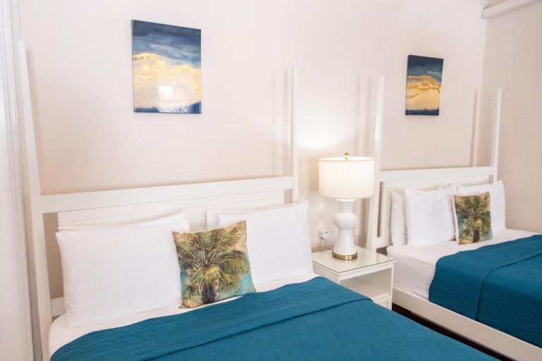 Habitación doble con camas en azul turquesa y decoración tropical en Sweetfield Manor Barbados
