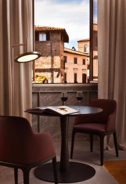 Rincón íntimo con mesa, copas de vino tinto y vistas a edificios históricos en The Bank Hotel Etruria Collection