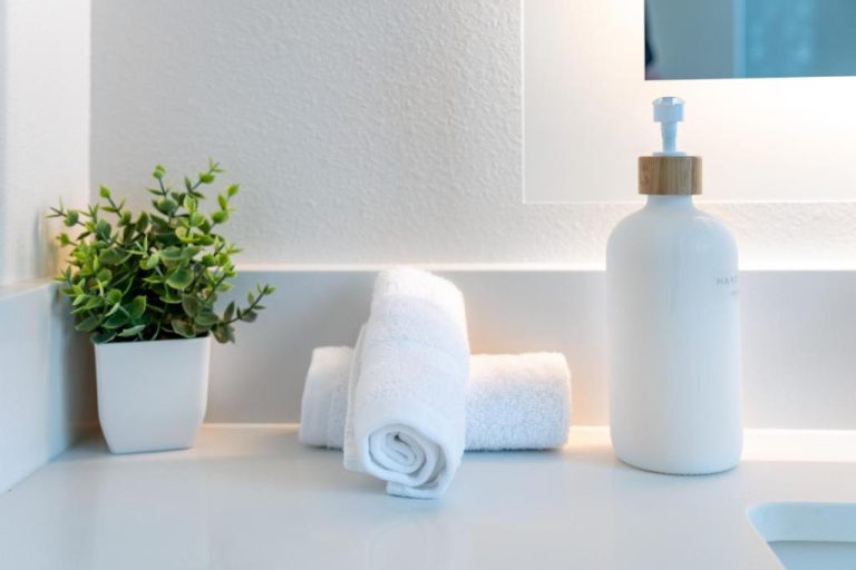 Baño de lujo con toallas blancas enrolladas, dispensador y planta en Luxury 2 Bedroom Residence