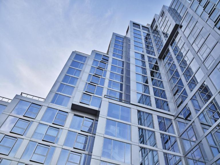 Fachada exterior de cristal del Conrad Los Angeles vista desde abajo con cielo azul de fondo