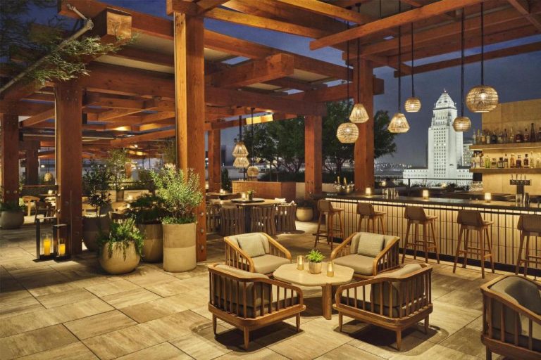 Terraza bar en la azotea del Conrad Los Angeles con vistas al Ayuntamiento de la ciudad al atardecer