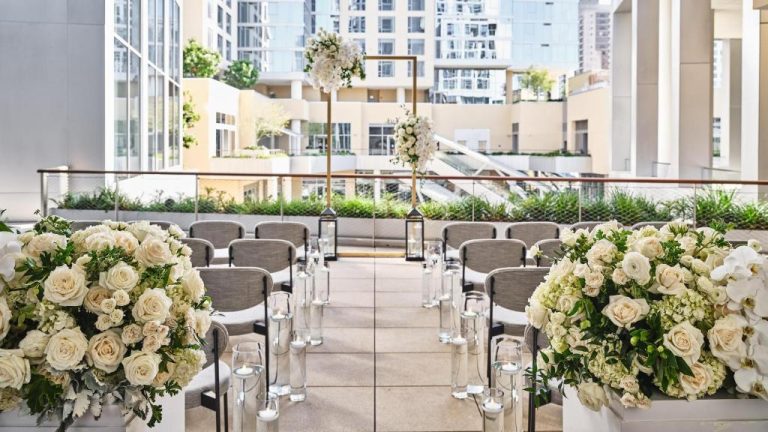 Ceremonia de boda en terraza exterior del Conrad Los Angeles con arco floral y decoración en blanco