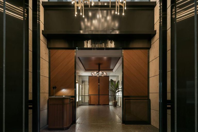 Elegante lobby de entrada del The Aoyama Grand Hotel con lámparas de diseño y revestimientos en madera oscura
