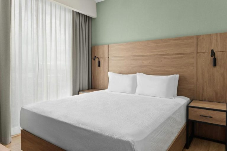 Habitación king con cabecero de madera y ropa de cama blanca en Residence Inn by Marriott El Coyol