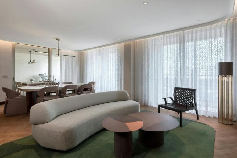 Elegante salón de suite con sofá curvo y comedor en The Landmark Nicosia Autograph Collection