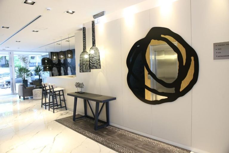 Lobby moderno del Ilum Experience Home con espejo decorativo negro y lámparas colgantes de diseño