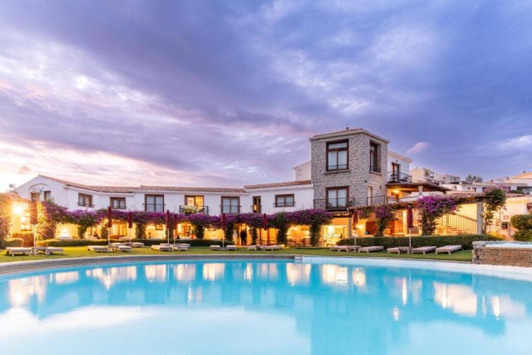 Piscina exterior al atardecer del Hotel Palumbalza Porto Rotondo con jardines y flores en Cerdeña