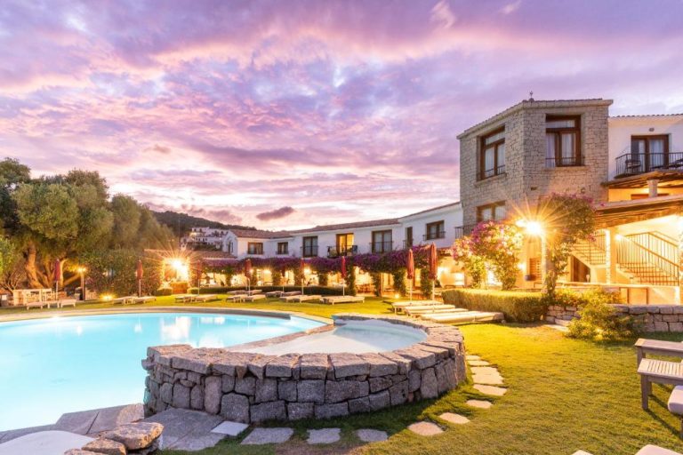 Piscina exterior al atardecer del Hotel Palumbalza Porto Rotondo con jardines iluminados en Cerdeña