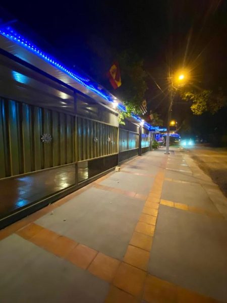 Fachada exterior iluminada del Hotel Solares de noche con luces azules y acera peatonal