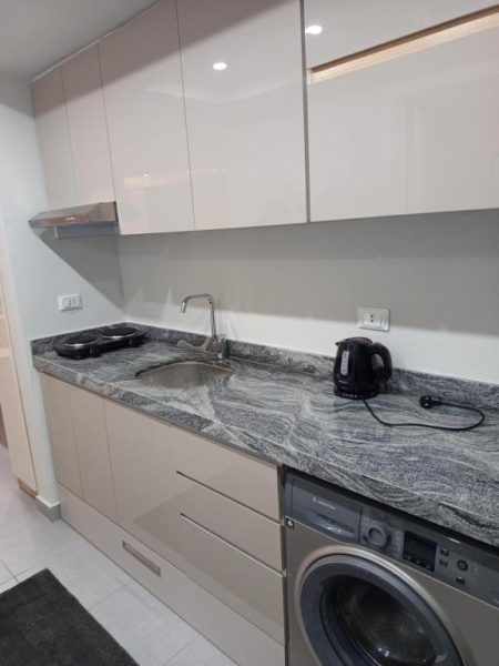 Cocina equipada con encimera de granito, fregadero y lavadora en Scandic Hotel Resort