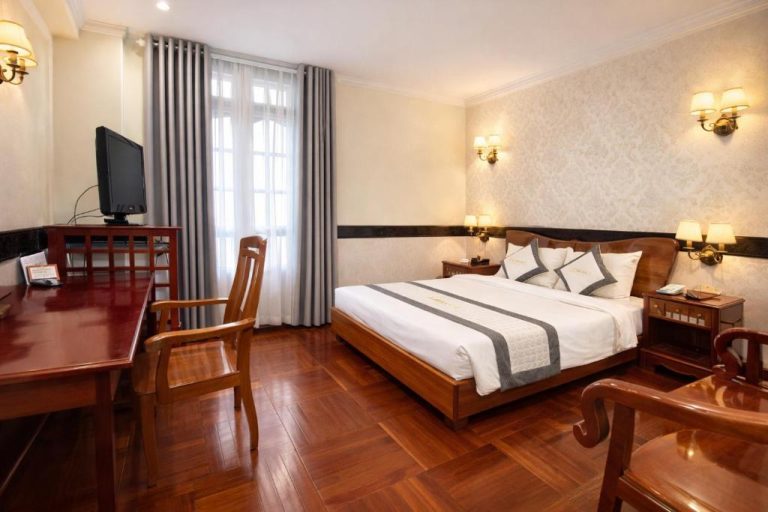 Habitación doble clásica con cama matrimonial, suelo de madera y escritorio en Orient Hotel