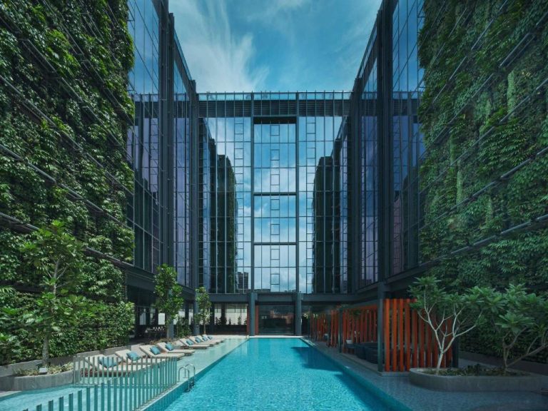 Piscina exterior con jardines verticales del Pullman Singapore Hill Street rodeada de fachadas acristaladas