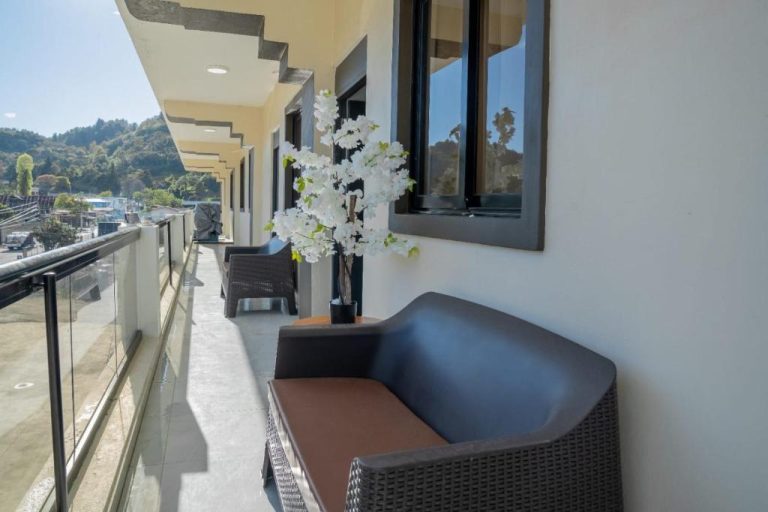 Terraza exterior del Hotel Bimini con sillones de ratán y vistas a la montaña en día soleado
