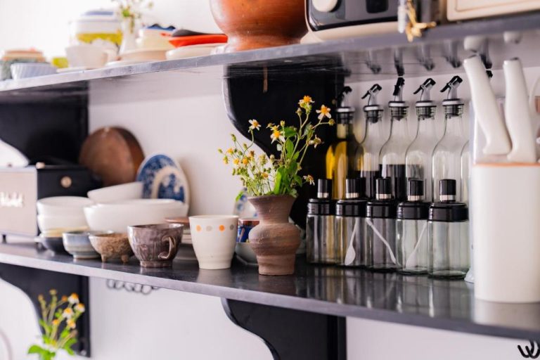 Estantes de cocina con vajilla artesanal, plantas y botellas de aceite en Y's La House