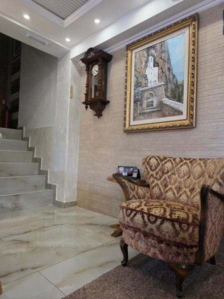Recepción clásica del Hotel Mažijanik con sillón antiguo, reloj de pared y cuadro decorativo