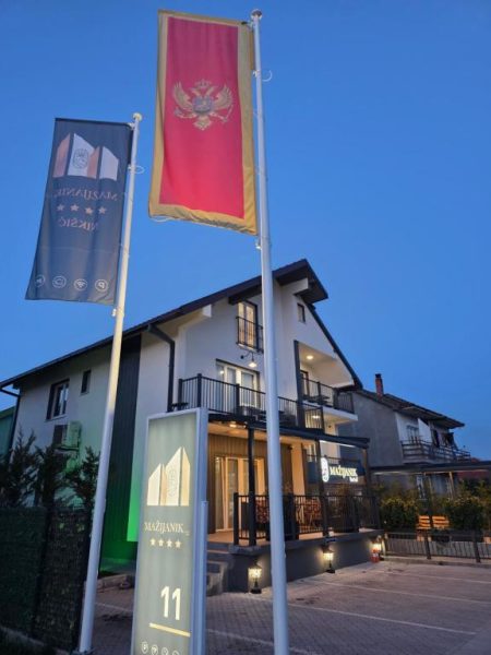 Fachada exterior del Hotel Mažijanik con banderas de Montenegro al atardecer