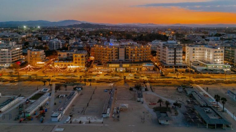 Vista aérea del Savoia Hotel Rimini al atardecer con la playa y el paseo marítimo iluminado